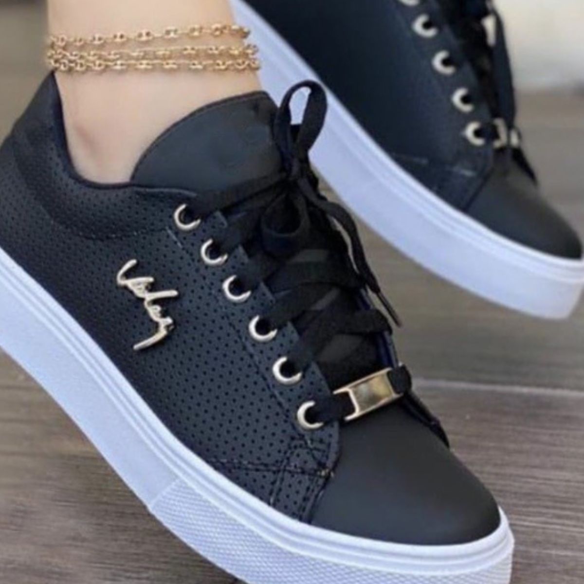 Black perforated lace-up sneakers with gold accents and white soles.