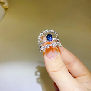 Sapphire and moissanite trio ring set in silver with blue oval sapphire center stone.