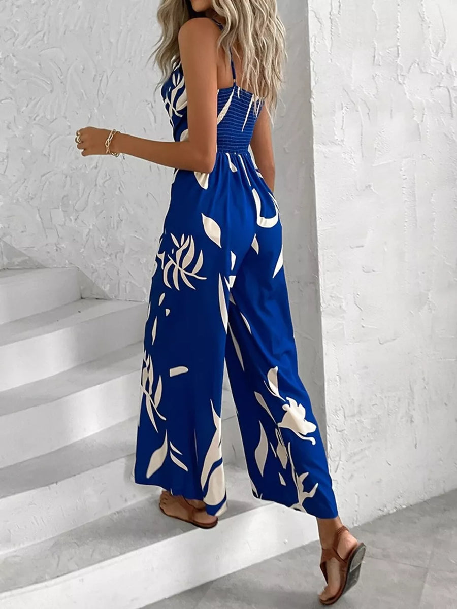 Royal blue abstract leaf print wide-leg jumpsuit with cinched waist and smocked bodice.