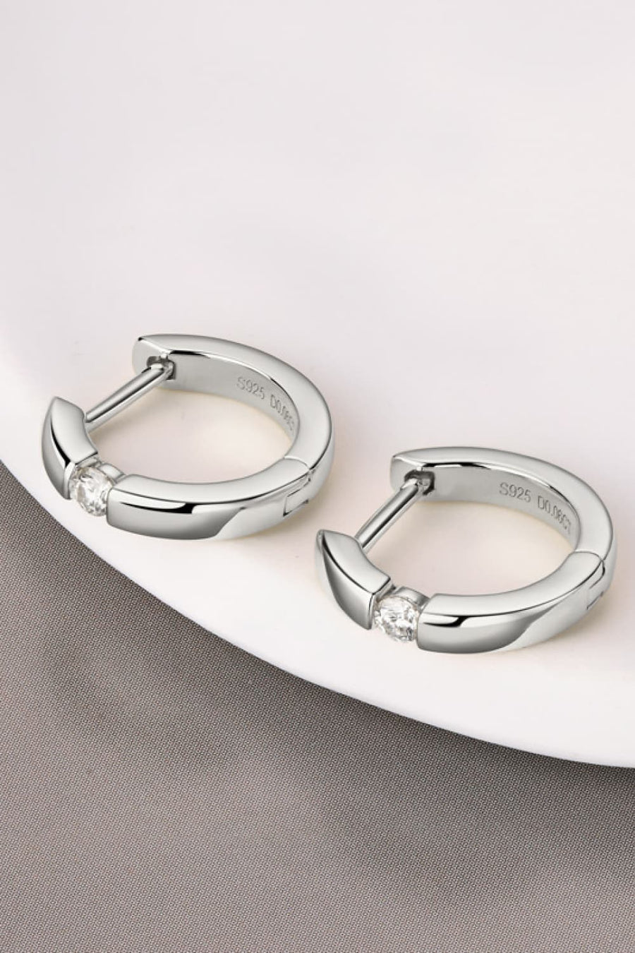 Silver pavé point huggie hoop earrings with a single clear stone detail.