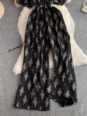 Black patterned jumpsuit with drawstring waist and wide legs.