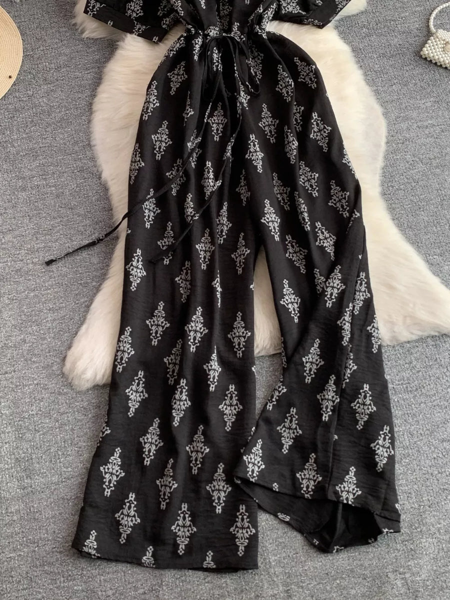 Black patterned jumpsuit with drawstring waist and wide legs.