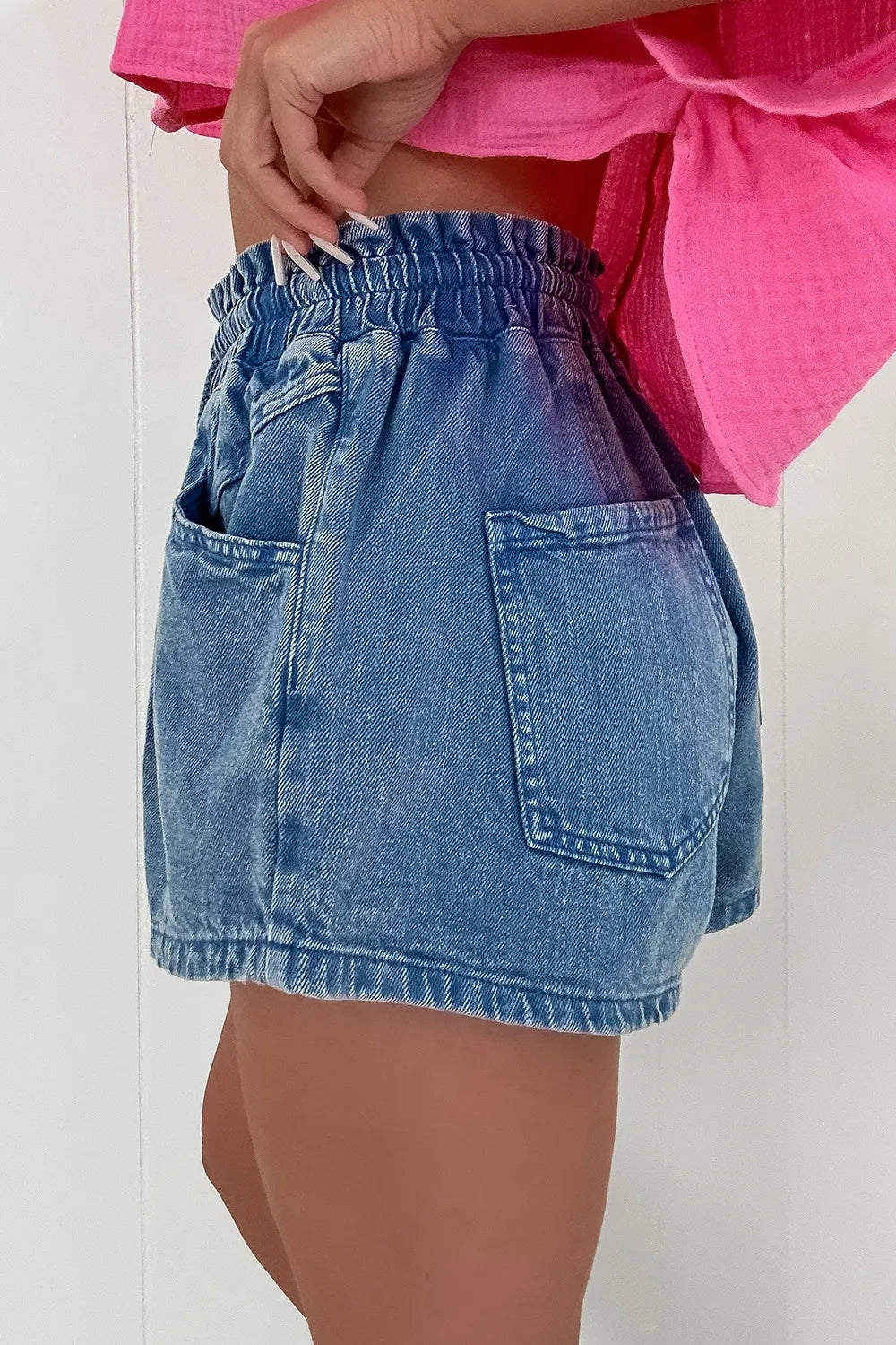Medium wash denim shorts with paperbag waist and relaxed fit.