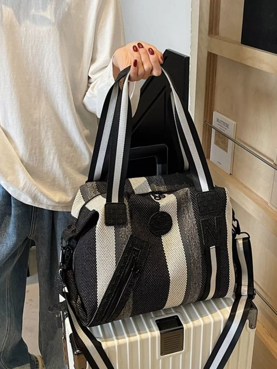 Chic striped duffle bag with black and white straps and detachable strap.