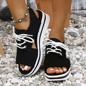 Black platform oxford sandals with white laces and a white striped sole.