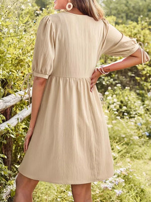 Apricot tied neck puff sleeve mini dress with cinched waist and tie detail on sleeves.