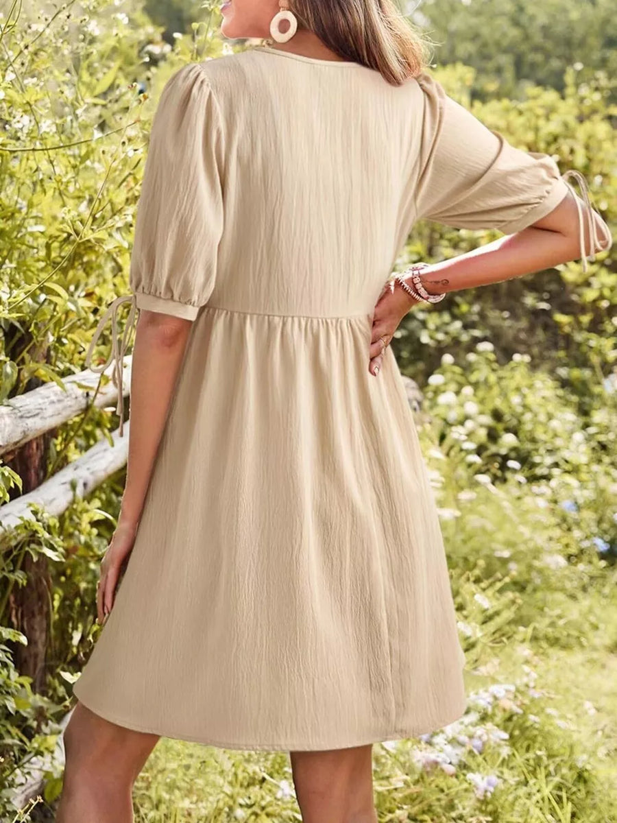 Apricot tied neck puff sleeve mini dress with cinched waist and tie detail on sleeves.