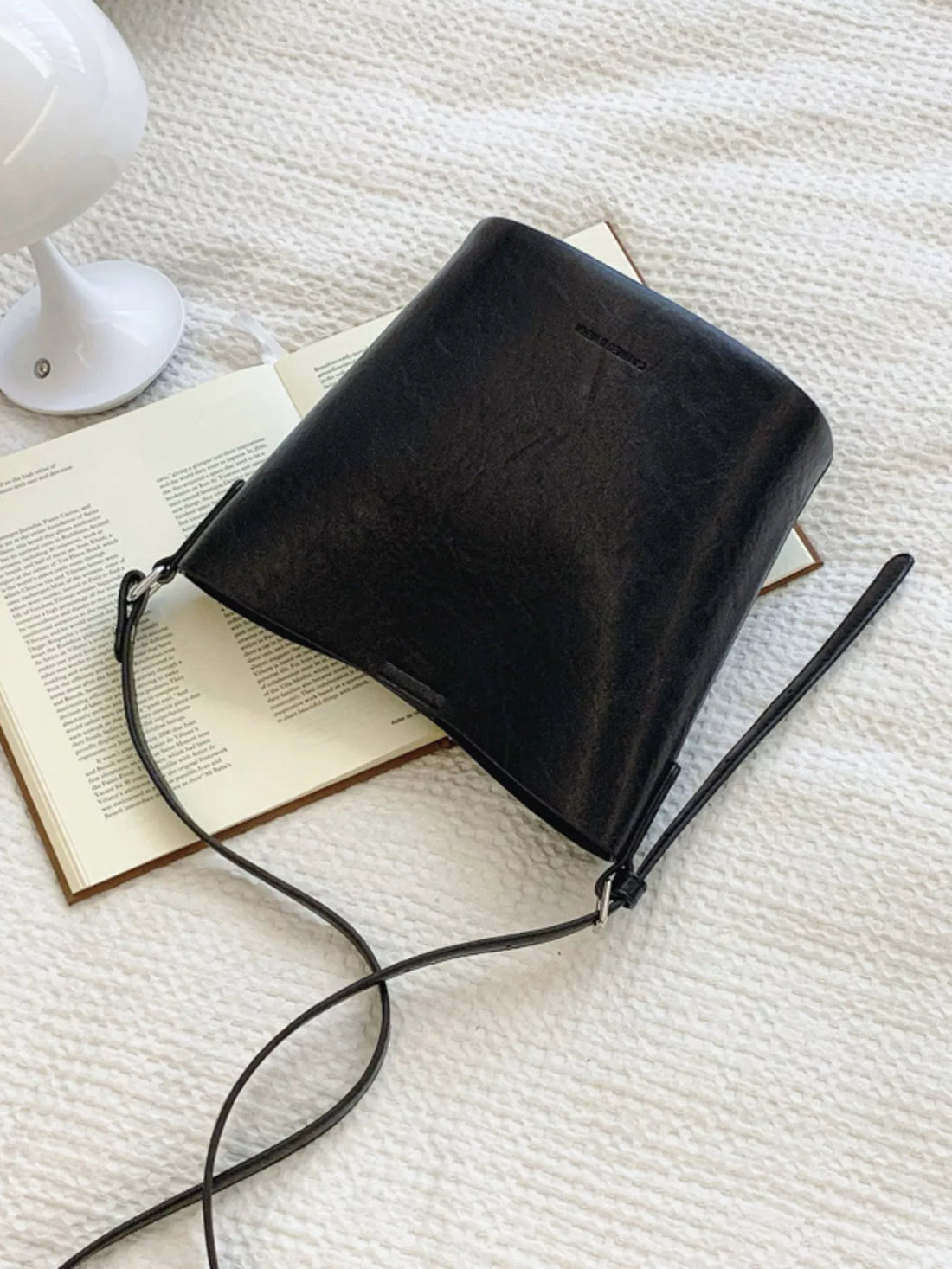 Sleek black leather bucket crossbody bag with adjustable strap