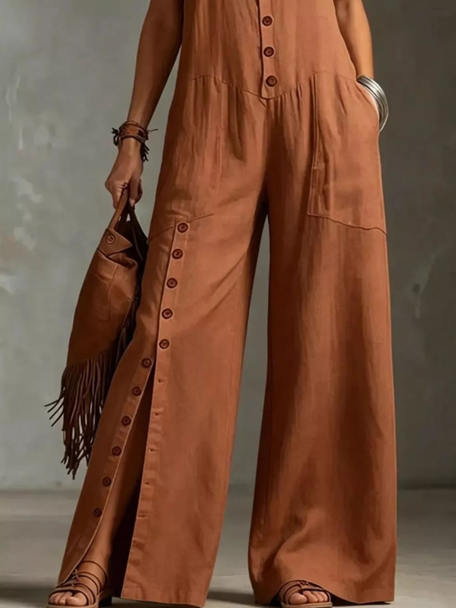 Caramel wide-leg jumpsuit with button details and pockets, styled with sandals and a fringe bag.