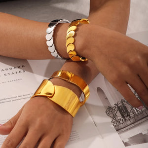 Gold cuff bracelet and gold leaf bracelet on arms