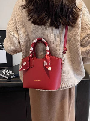 Red pu leather bucket bag with polka dot scarf detail and adjustable strap.