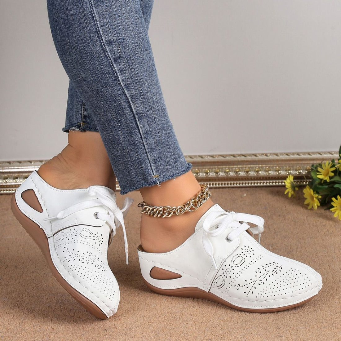 White perforated slip-on mules with lace-up detail and cut-out sides.