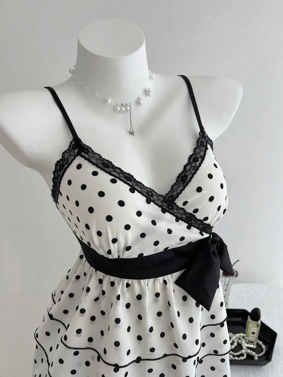White polka dot camisole with black lace trim, black ribbon tie, and ruffled hem.