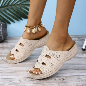 Beige laser-cut comfort slide sandals with floral and circular cutouts.
