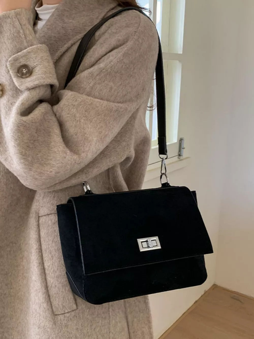 Sleek black suede crossbody bag with silver turn-lock closure and flap.