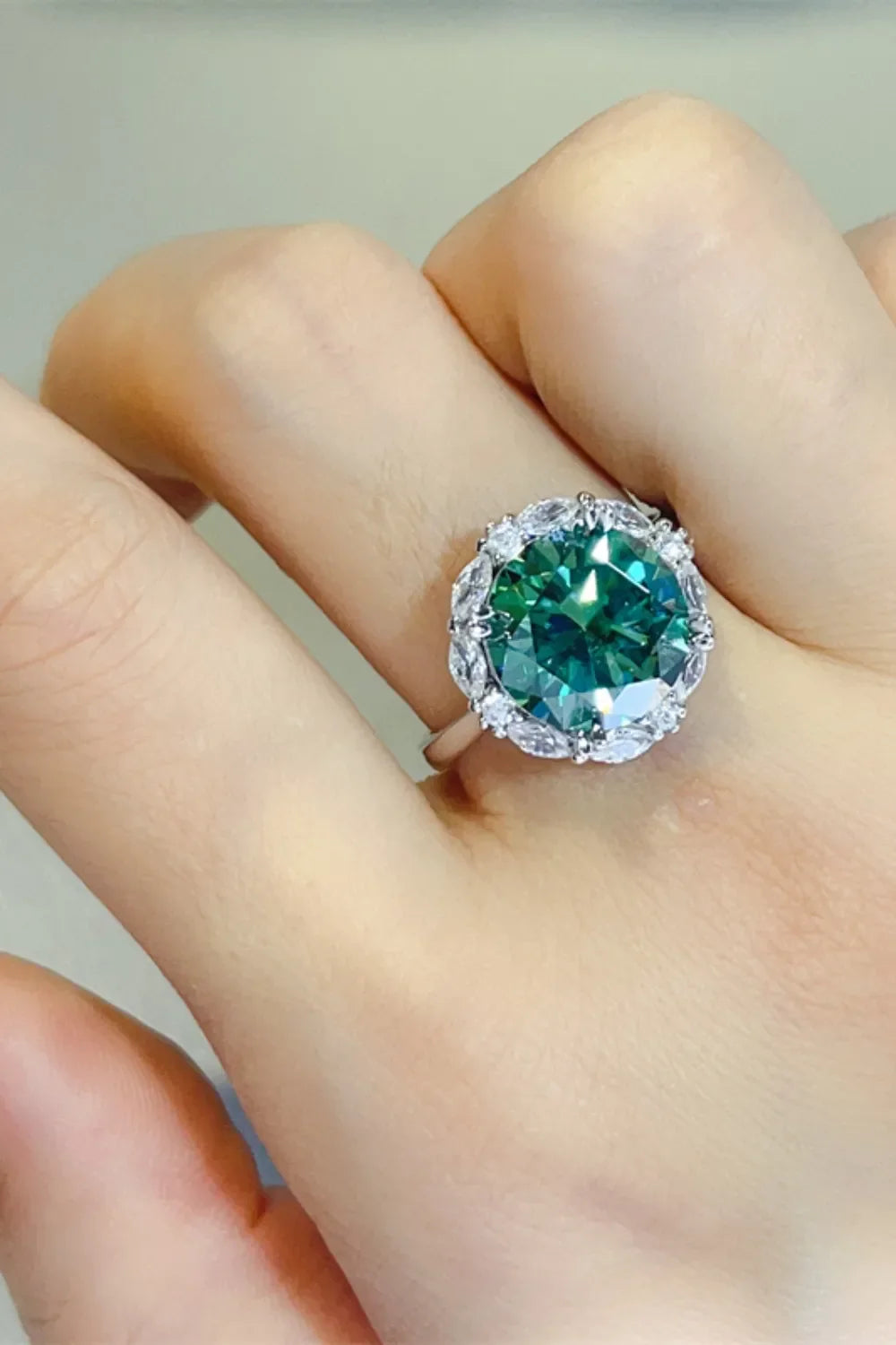 Emerald halo sterling silver cocktail ring with dark green center stone and clear accent stones.