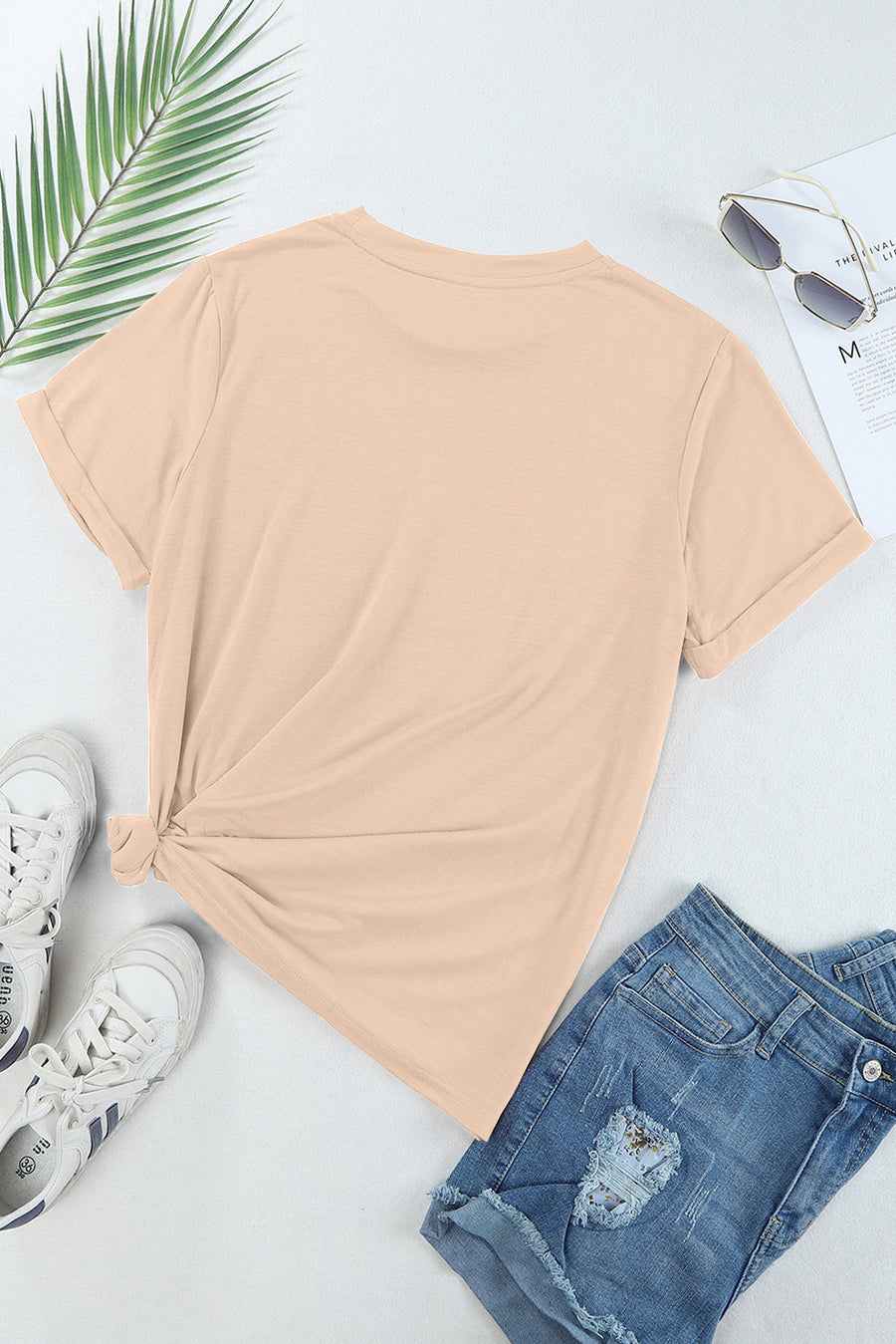 Tan casual t-shirt with rolled sleeves and a knotted hem, styled with denim shorts and sneakers.