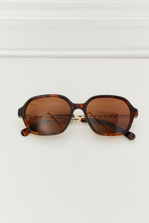 Tortoiseshell hexagonal frame sunglasses with brown lenses and gold chain detail
