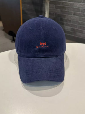 Navy baseball cap with red embroidered "feel" text and curved brim
