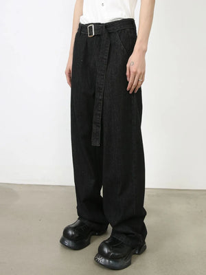Black denim wide-leg trousers with a belted waist and sculptural silhouette.