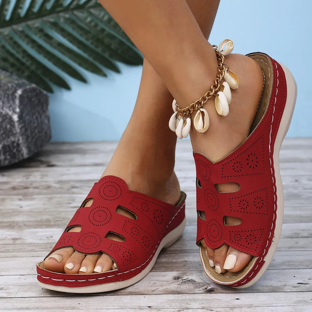 Deep Red laser-cut comfort slide sandals with decorative perforations and a seashell anklet.