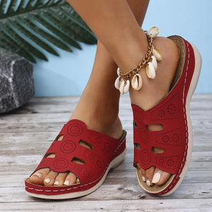 Deep Red laser-cut comfort slide sandals with decorative perforations and a seashell anklet.