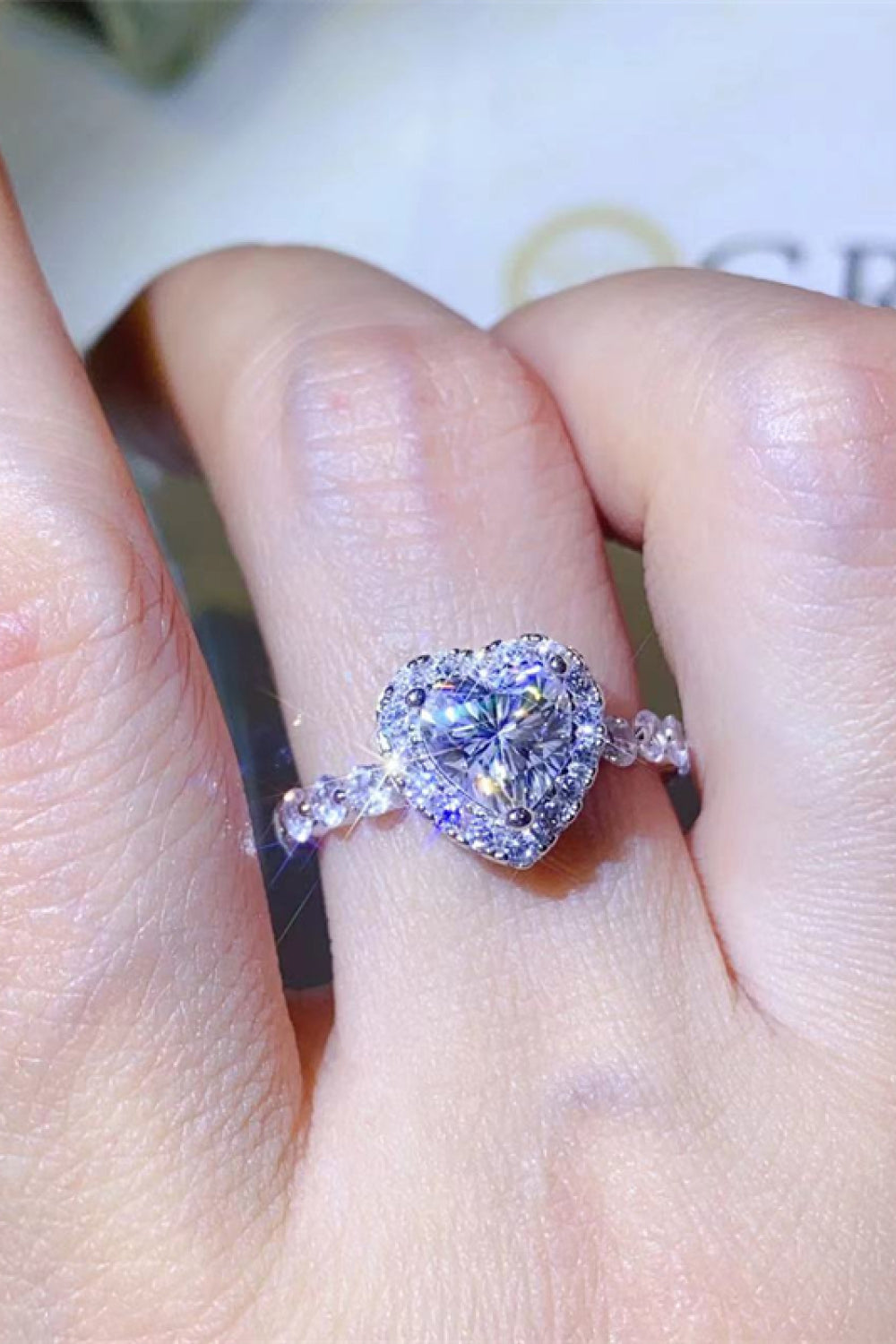 White gold halo ring with a heart-shaped moissanite center stone and diamond band.