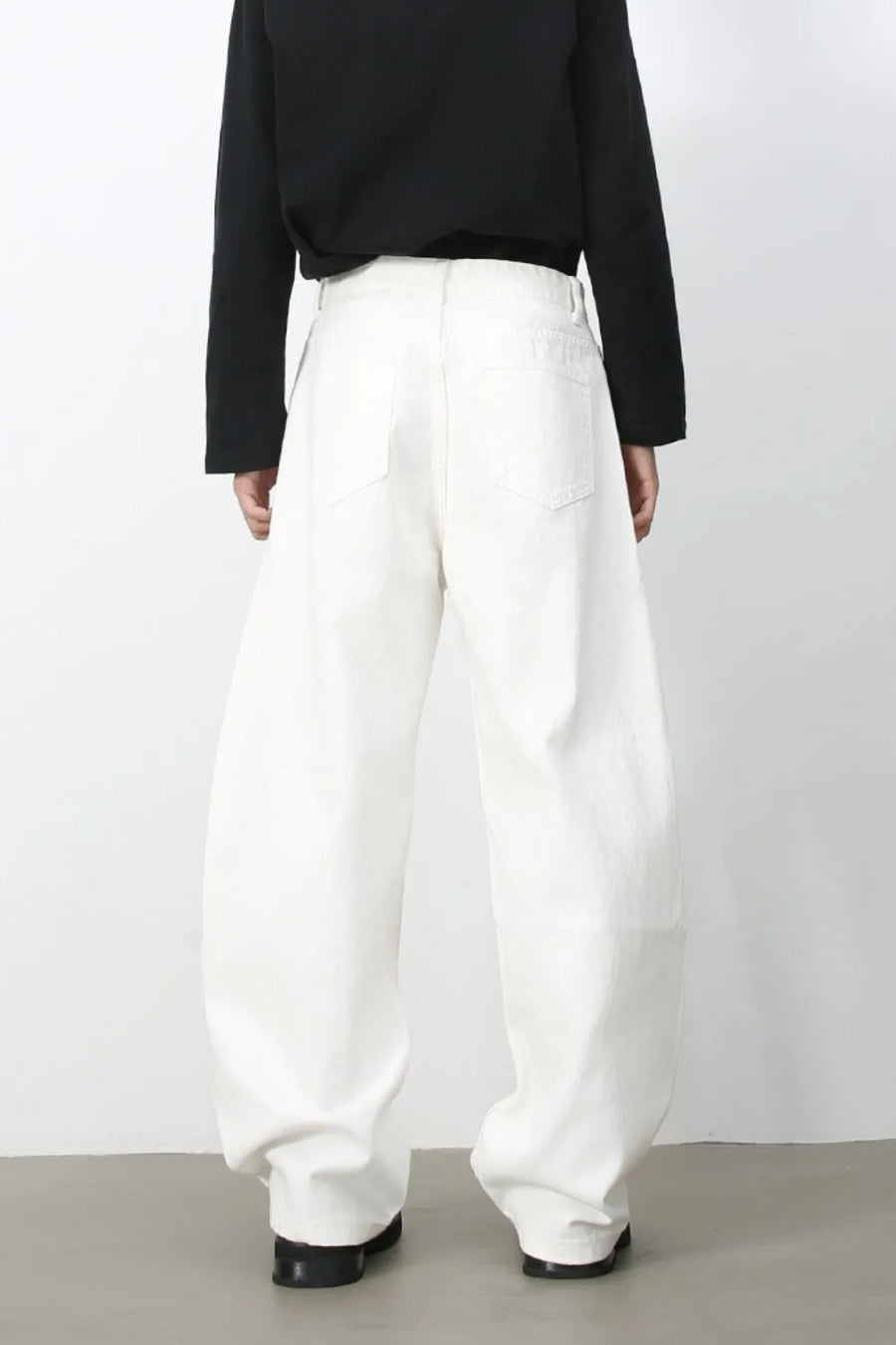 Sculpted white denim balloon trousers with a high waist and wide leg, shown from the back.
