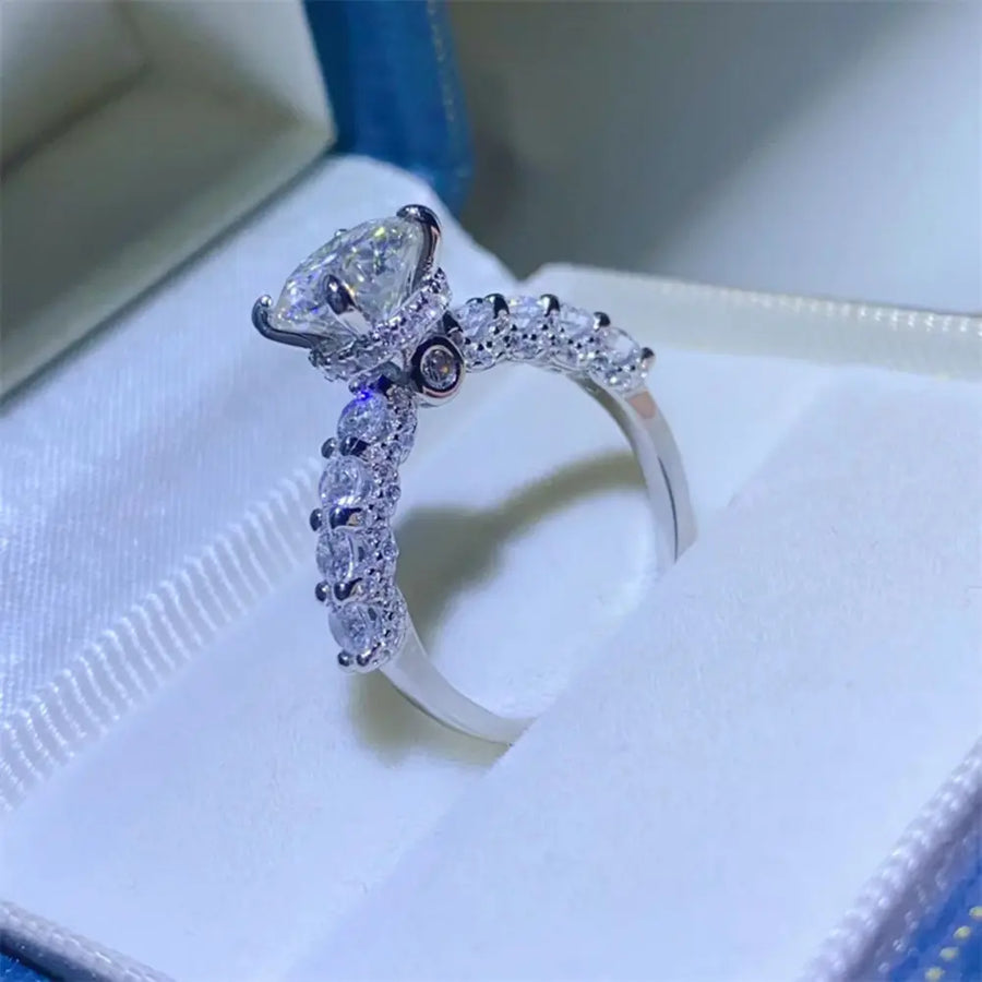 Silver moissanite halo ring with pavé band and marquise cut center stone.