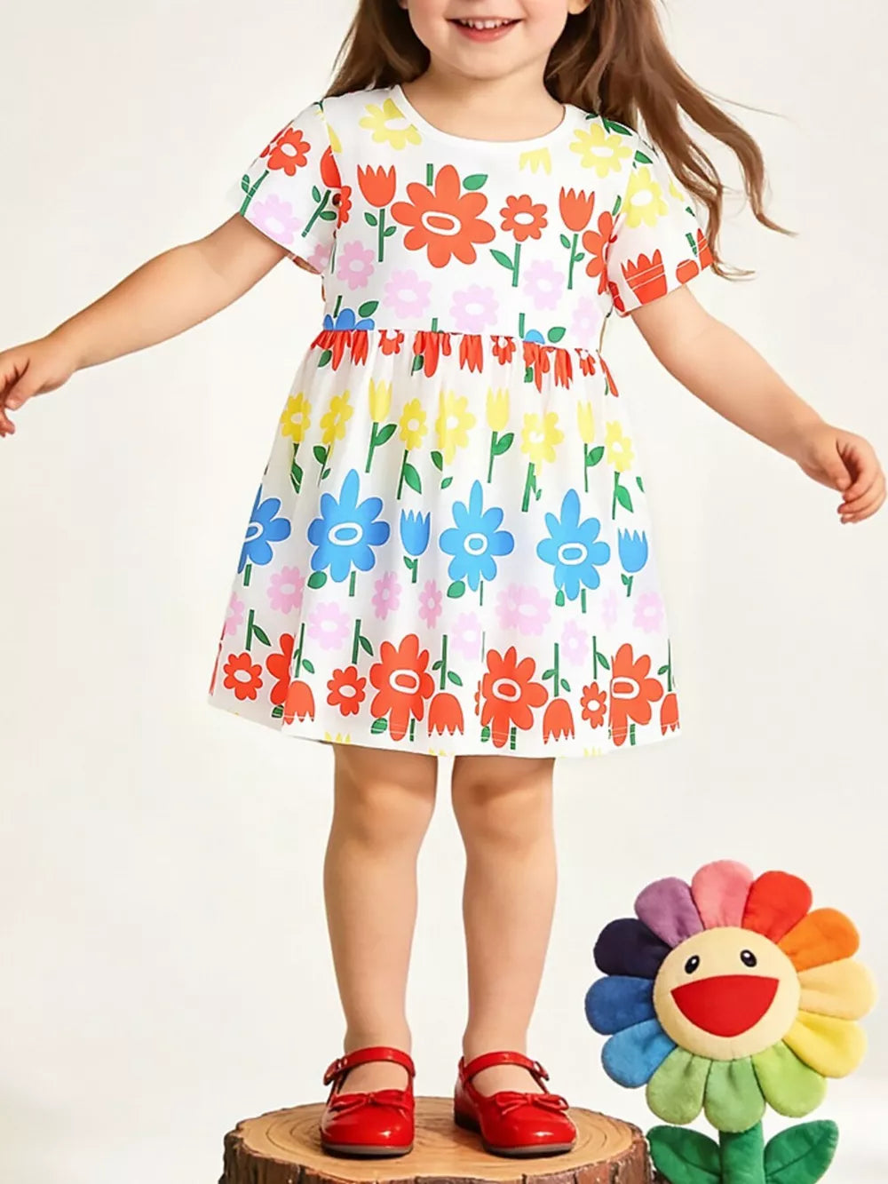 Toddler cotton dress with a whimsical allover floral print in red, blue, yellow, and pink.