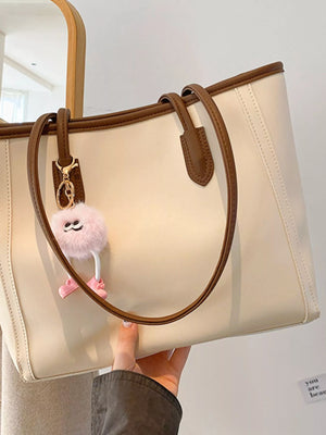 Beige PU leather tote bag with brown trim and a fluffy pink charm.