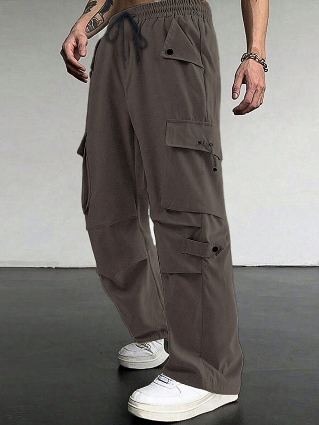 Brown cargo pants with multiple pockets and drawstring waist, styled with white sneakers.