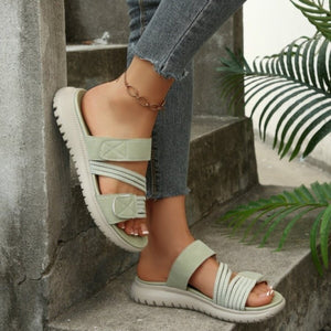 Green multi-strap sandals with adjustable closure and criss-cross elastic detail.