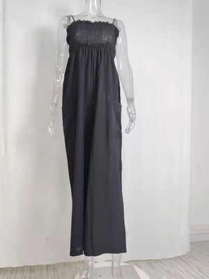 Black smocked wide leg romper with pockets and spaghetti straps.