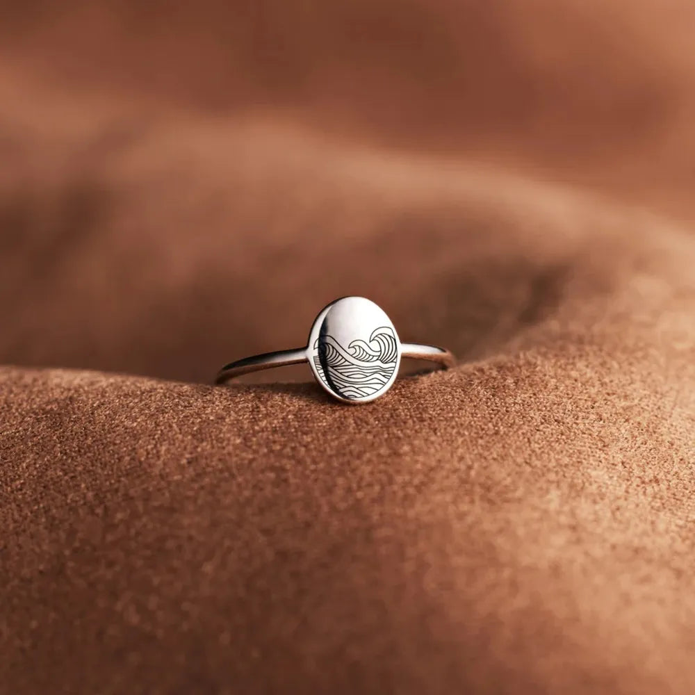 Silver band ring with oval top engraved with a wave pattern