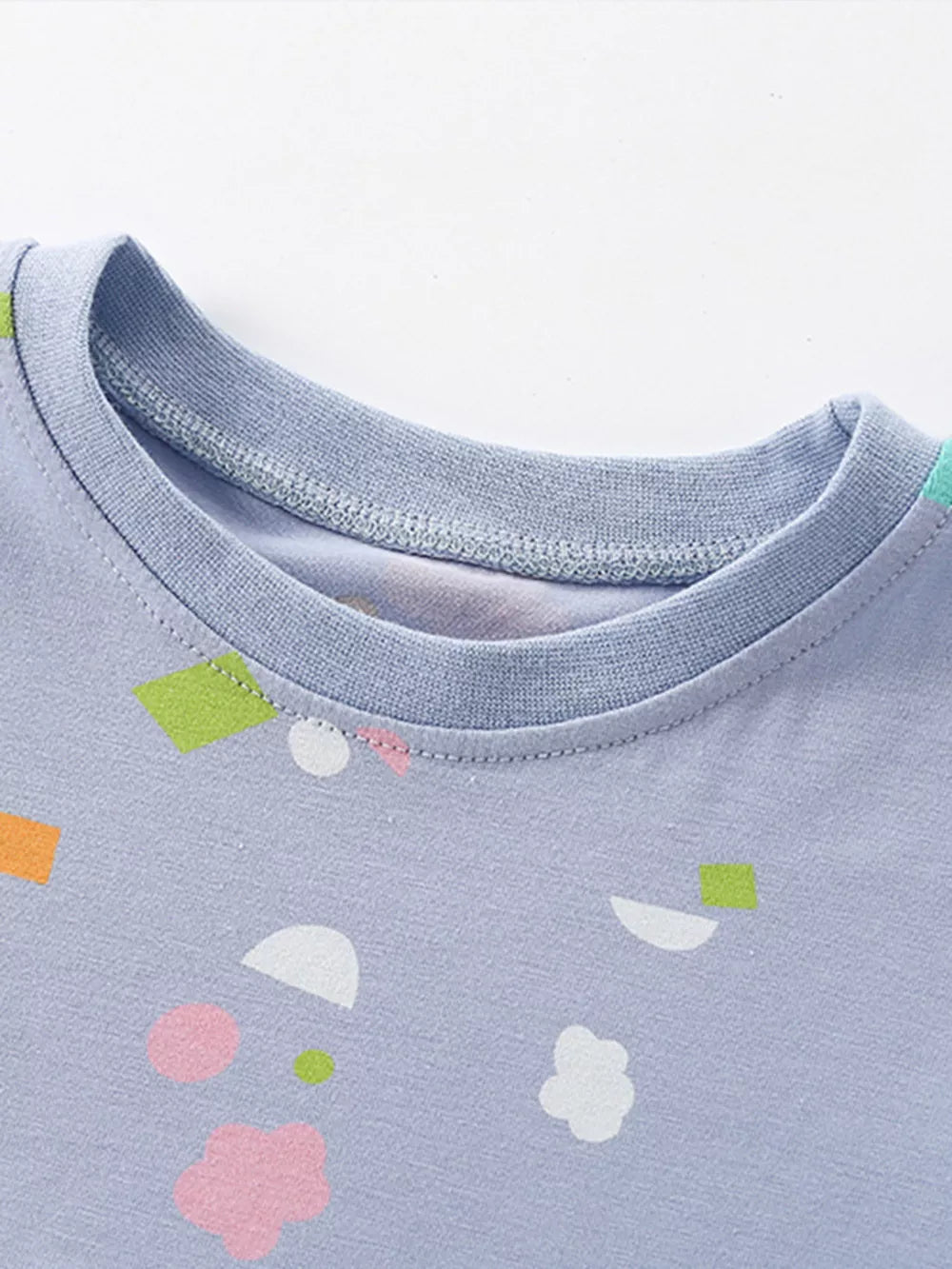 Baby dress with playful abstract shapes in pastel colors on a light blue cotton blend fabric.