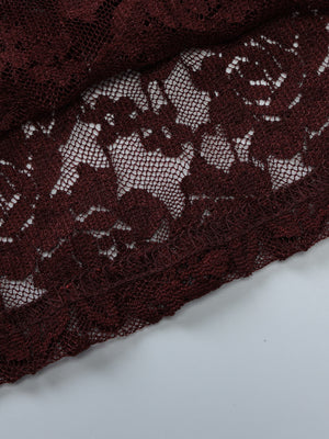 Sheer lace one-shoulder top in burgundy with floral pattern and scalloped hem detail.