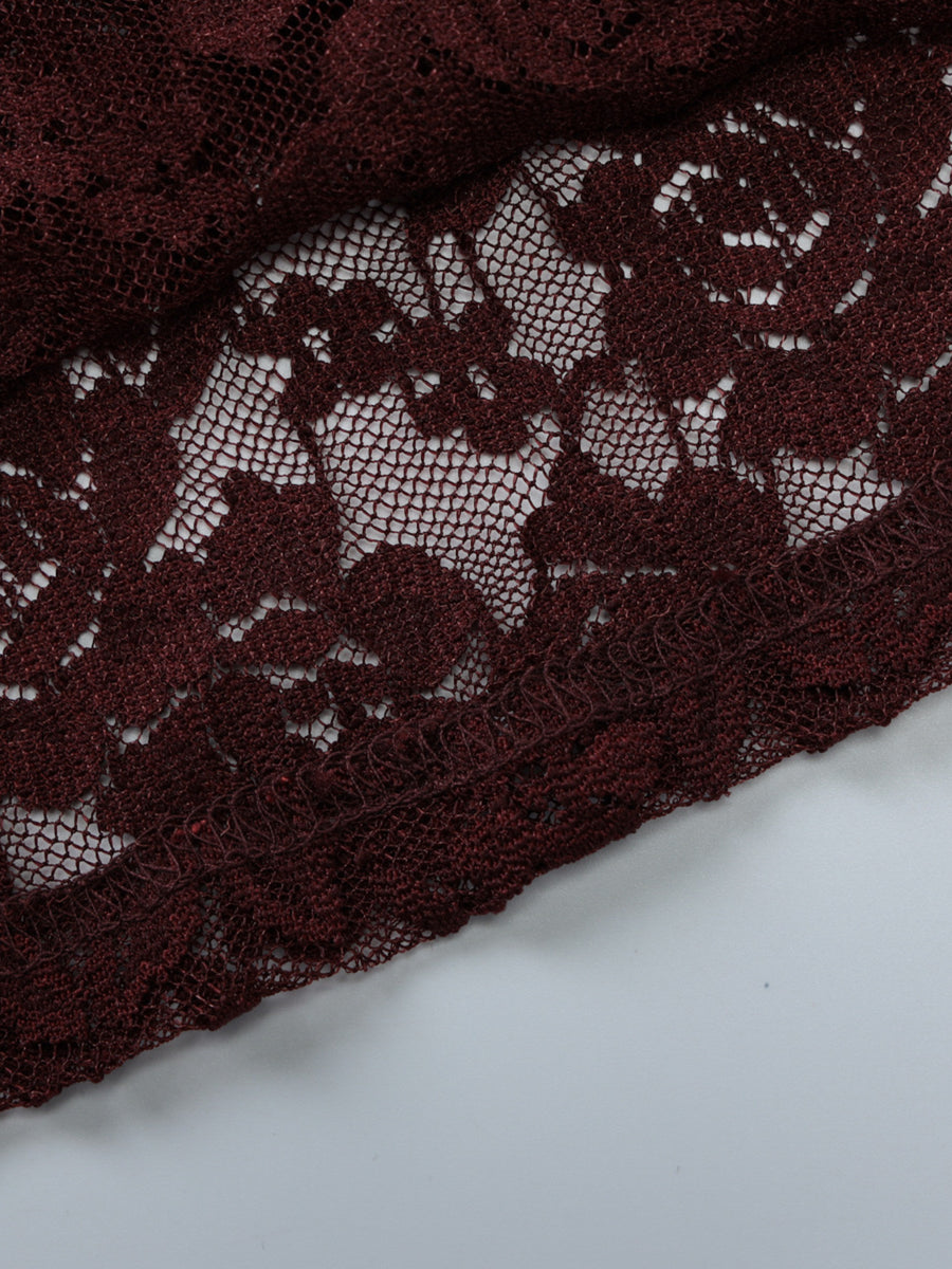 Sheer lace one-shoulder top in burgundy with floral pattern and scalloped hem detail.