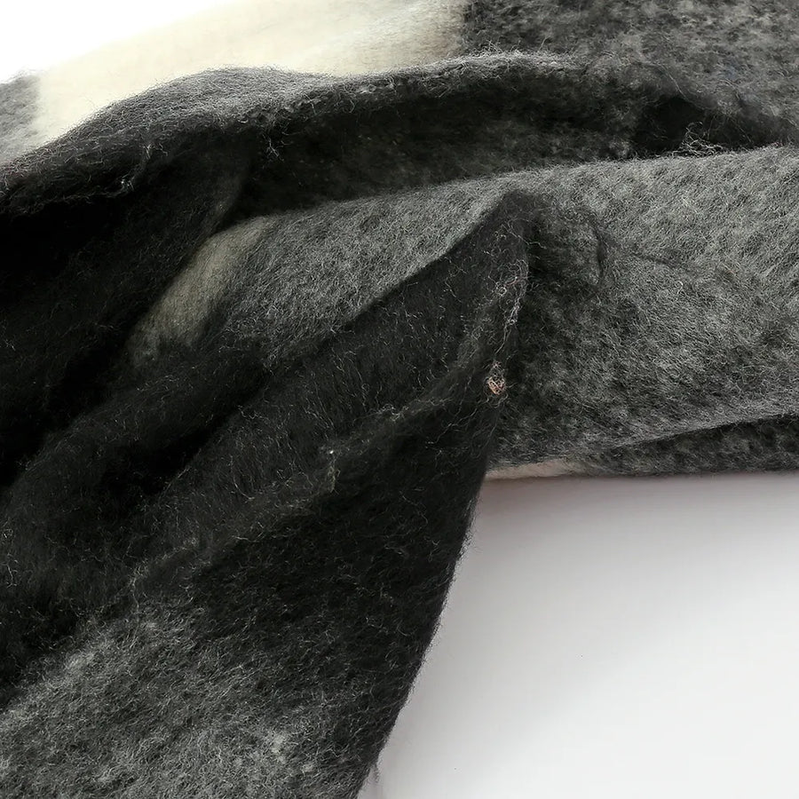 Checked plaid fluffy scarf in black and grey with white accents and fringe detail.