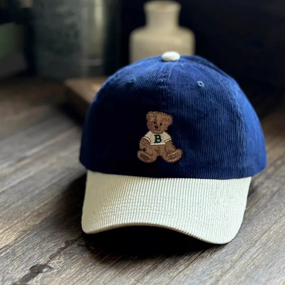 Corduroy baseball cap in navy and tan with embroidered bear detail.