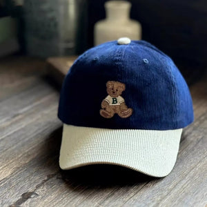 Corduroy baseball cap in navy and tan with embroidered bear detail.