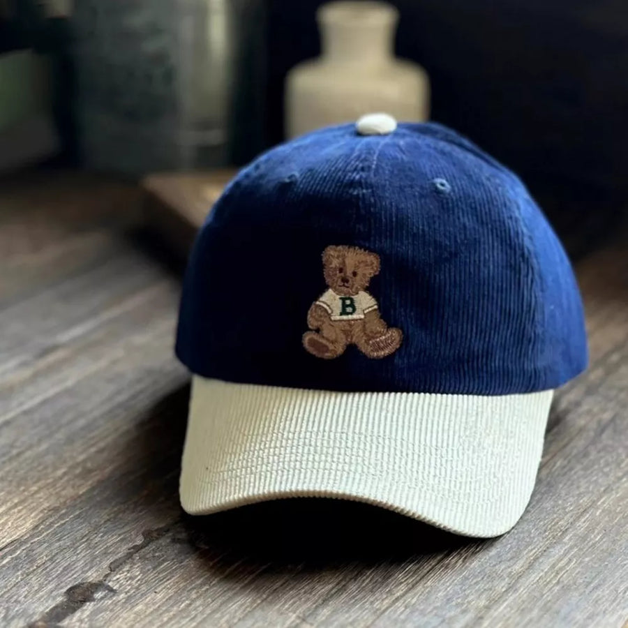 Corduroy baseball cap in navy and tan with embroidered bear detail.