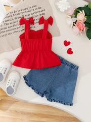 Red bowknot strap top with ruffled hem and denim shorts with ruffled hem.