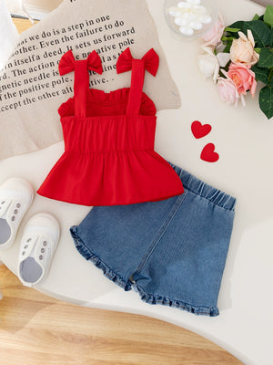 Red bowknot strap top with ruffled hem and denim shorts with ruffled hem.