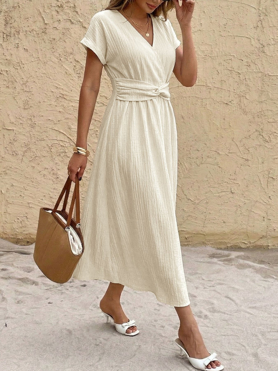 Beige cotton blend midi dress with V-neck, short sleeves, and twisted knot waist detail.
