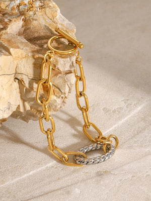 Gold two-tone link toggle bracelet with a twisted accent chain.