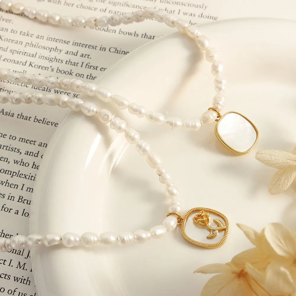 Gold baroque pearl necklace with floral medallion charm and white stone pendant