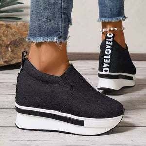 Black round-toe slip-on platform shoes with white text detail on the heel and chunky sole.