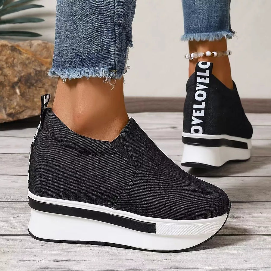 Black round-toe slip-on platform shoes with white text detail on the heel and chunky sole.