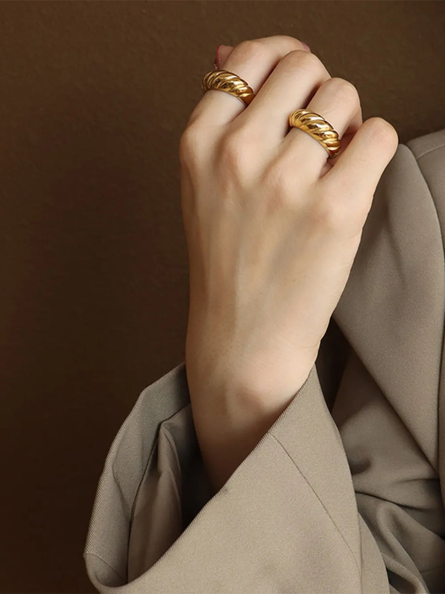 Gold sculpted steel croissant ring with twisted band detail.